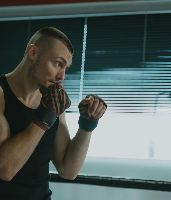 Man in a focused stance performing a strength exercise in a dark gym.